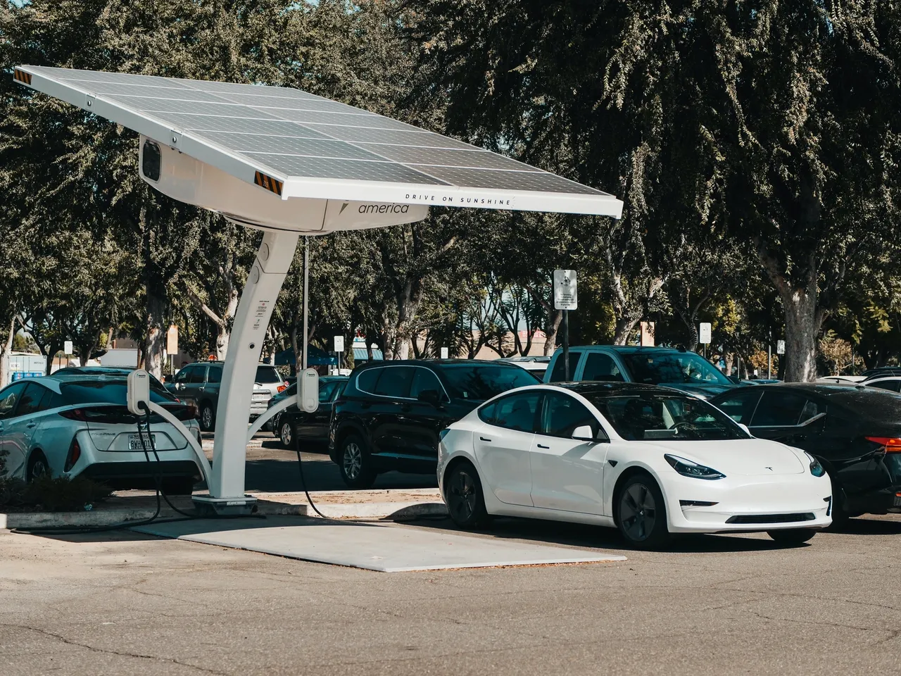 Una placa solar carga mediante un punto de carga eléctrico a un Tesla blanco.