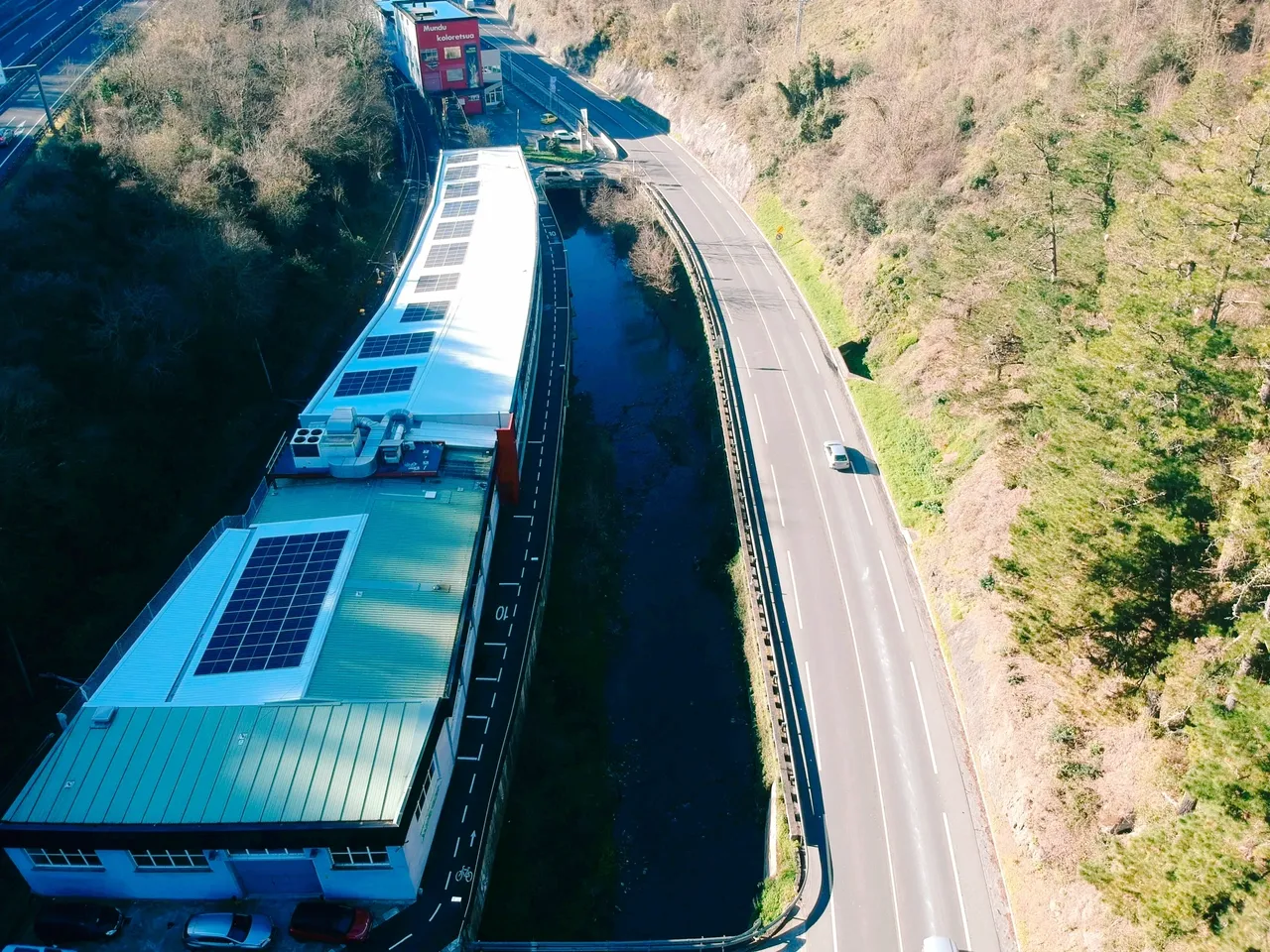 Edificio pegado a la carretera con placas solares en el tejado.