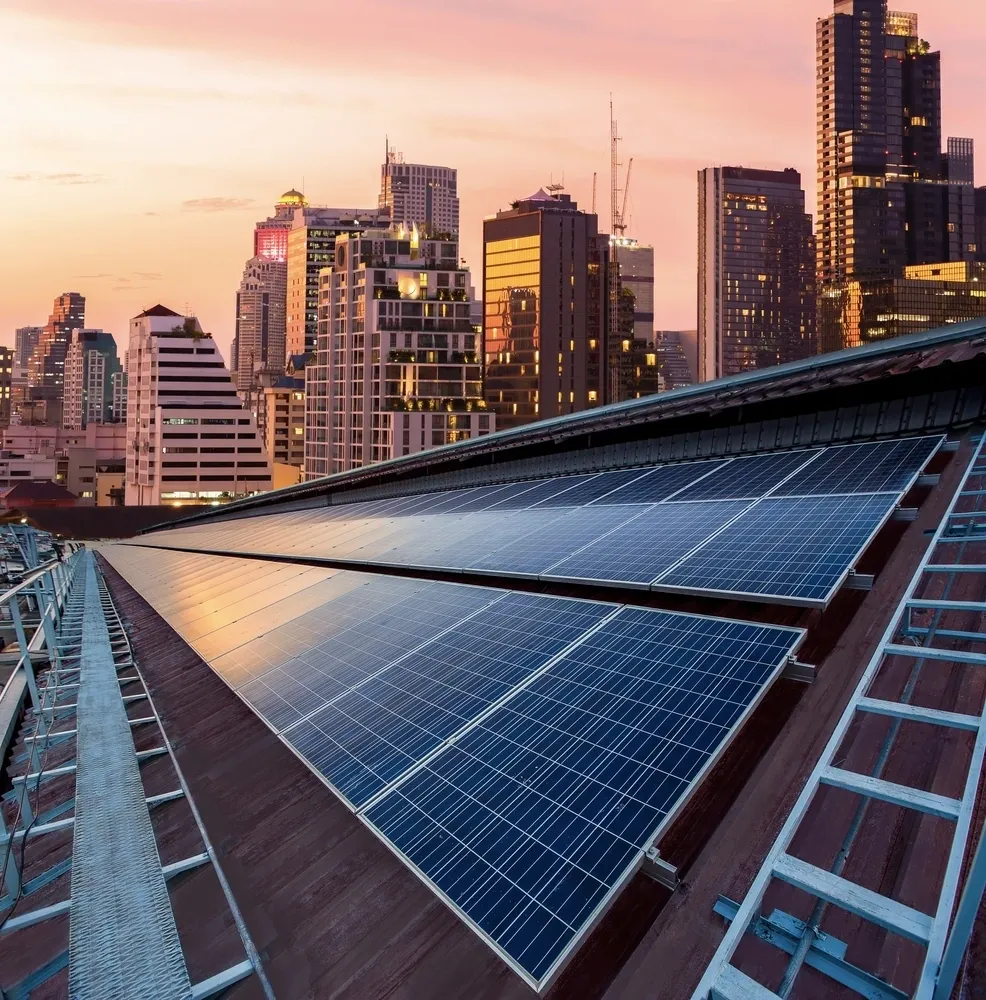 Placas solares en lo alto de un edificio en una ciudad con rascacielos.