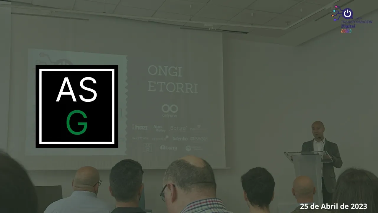 Un hombre adulto habla en una conferencia, mientras se encuentra superpuesto en la imagen un logotipo de ASG encima.
