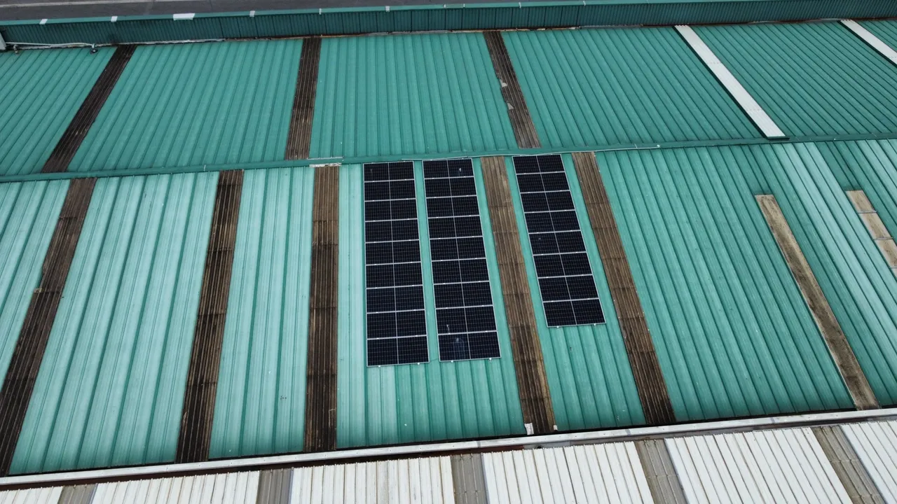 Vista aérea de unos tejados de chapa de unas naves con placas solares.