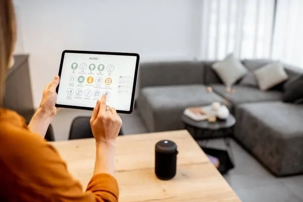Una mujer revisa una app en su tablet mientras se encuentra en el salón de su casa.