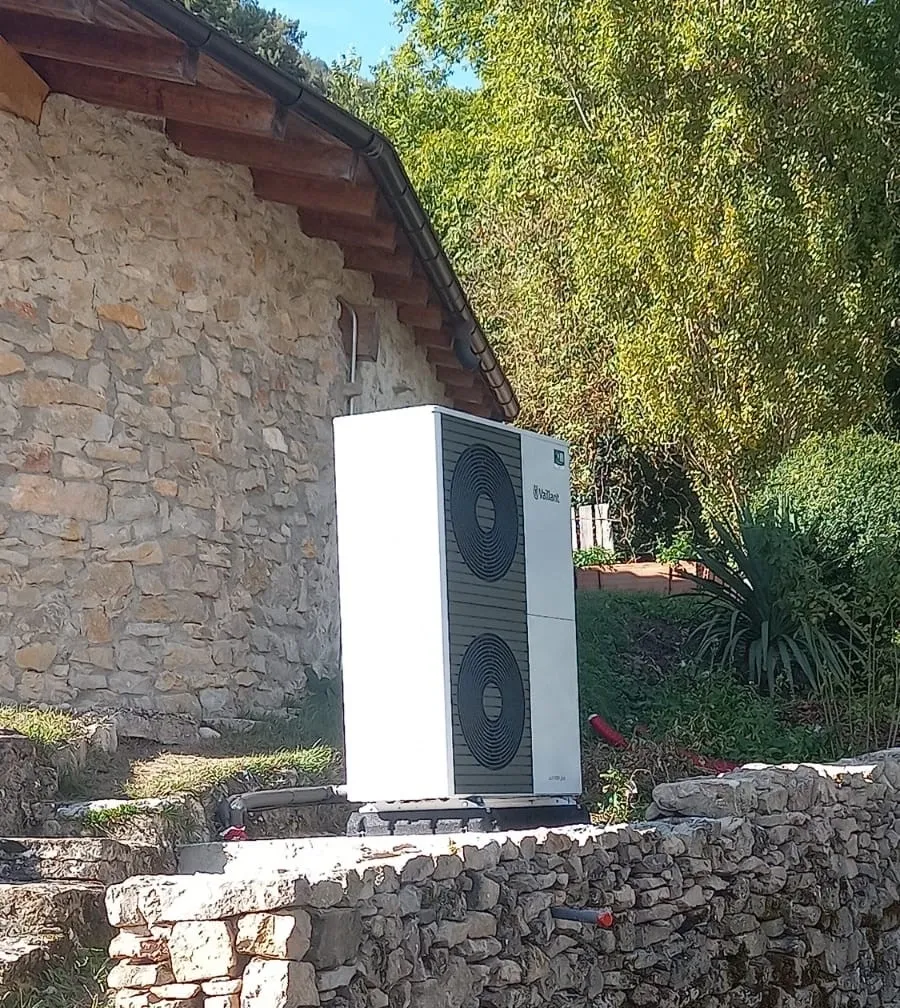 Máquinas de aerotermia en el exterior de una casa de piedra.