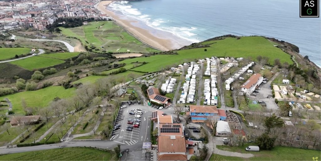 Vista aérea de un camping con placas solares al lado de un acantilado.
